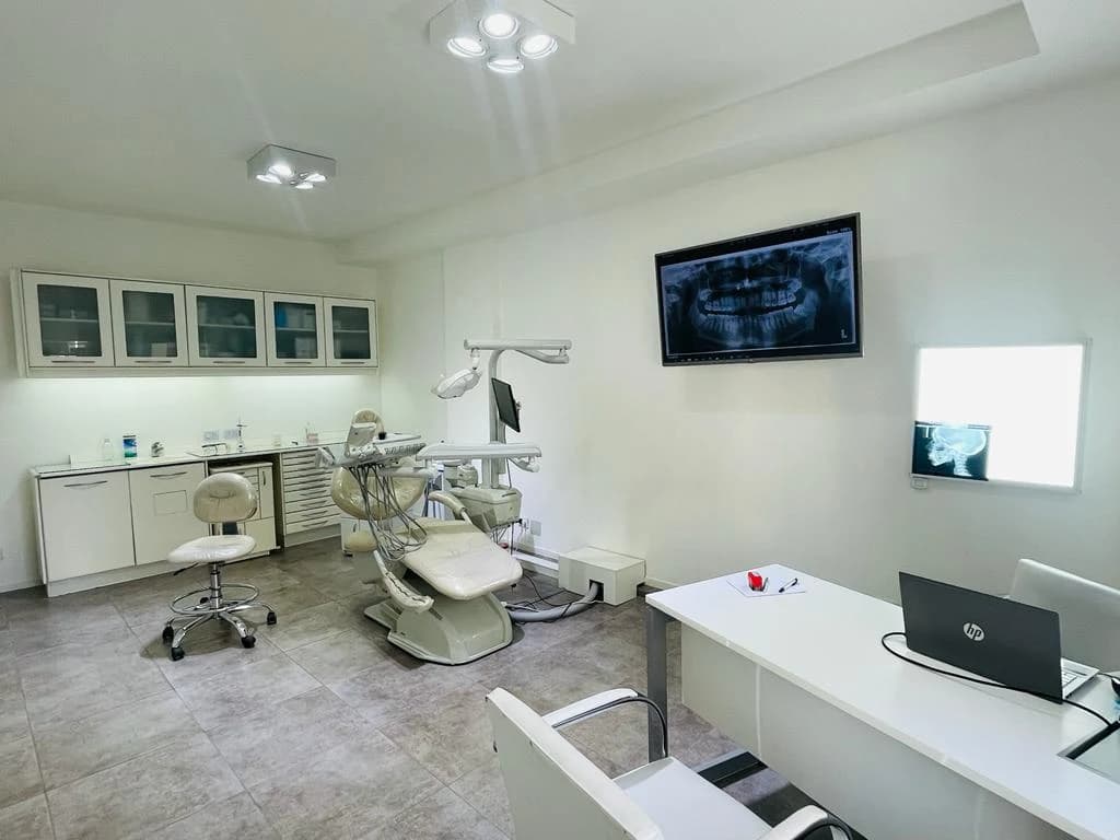 Consultorio con sillón odontológico y monitor con radiografía panorámica